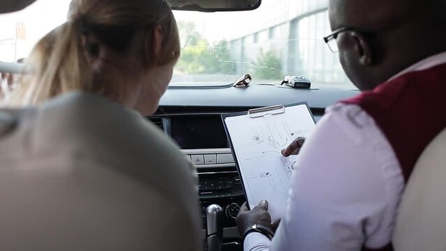 Driving school concept video. A car instructor teaches a young woman how to drive. Teaching the rules of the road and driving a vehicle