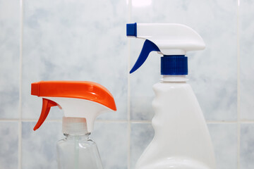 Two plastic cleaning spray bottles on a tiled background in a bathroom. Detergent chemical agent in...