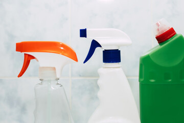 Various spray bottles with detergent on the background of tiles in the bathroom. The concept of...