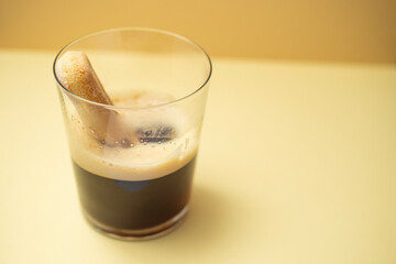 Spongy ladyfinger cookie dipped in espresso coffee, in a transparent glass