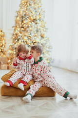 a boy and a girl near a Christmas tree with sweet New Year's candies