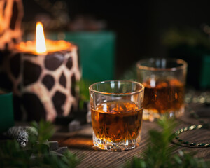 Two glasses of whiskey or bourbon with Christmas decoration on dark background. New Year, Christmas and winter holidays whiskey mood concept