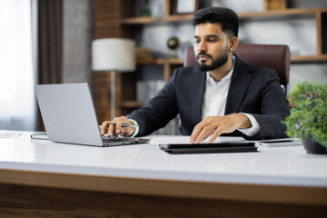 Focus on hands confident businessman wearing suit writing notes or financial report, sitting at desk with laptop, focused serious man working with paper documents student studying online research work