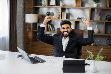 Excited screaming young bearded business man or entrepreneur working with laptop computer and...