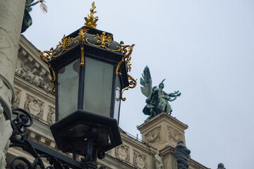 Fototapeta na wymiar Antique lamp post near Lviv State Academic Opera and Ballet Theatre. Theatre was built in classical tradition of Renaissance and Baroque architecture. The building is crowned by large bronze statue.