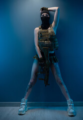 sexy soldier girl armed with an automatic rifle, in military clothes on a blue background