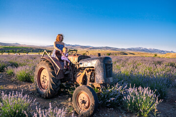 Gorgeous mountain landscape with lavender flowers. Woman on an old tractor in a lavender field. Beautiful rural sunset evening © R