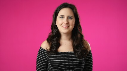Fototapeta premium Smiling attractive brunette young woman 20s 30s years old posing isolated on pink background studio. People sincere emotions lifestyle concept. Looking at camera with charming smile