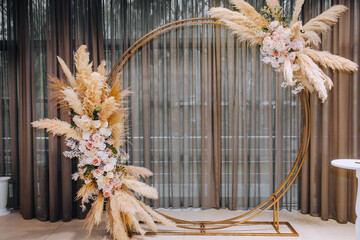 A beautiful round arch made of reeds, roses, wild flowers stands in the restaurant at the ceremony....