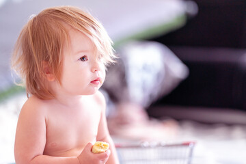A cute toddler is having a snack. Portrait of a child eating a banana