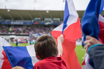 Un enfant dans les tribunes du stade, brandit le drapeau français bleu blanc rouge - obrazy, fototapety, plakaty