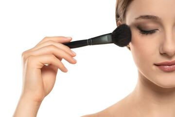 Woman using make-up brush, isolated on white background