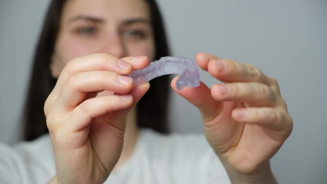 A woman showing dental mouthguard, splint for the treatment of dysfunction of the temporomandibular joints, bruxism, malocclusion, to relax the muscles of the jaw.
