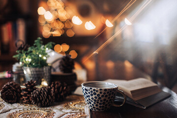 book and cup on a dark table with glittering lights background
