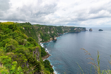 Fototapeta na wymiar Beautiful coastline view from Saren Cliff Point. Clear water and rocks with cloudy sky. Nusa Penida, Indonesia.