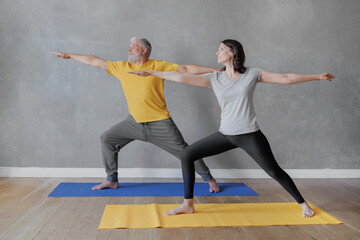 man and woman do yoga in sports studio, hero pose. senior coach and young adult female meditate, exercise. relaxation, relaxation practices and health care