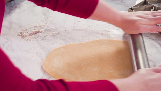 Rolling out sugar cookie dough to bake Christmas cookies.