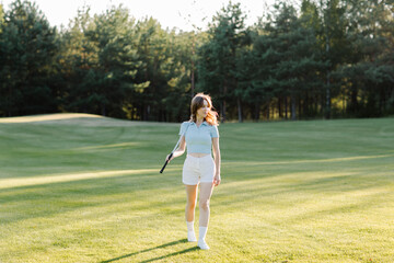 Woman golfer walking on green golf course. High quality photo