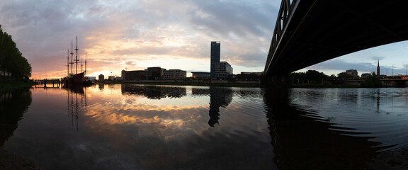 sunset at the river Weser in Bremen with reflection of the office buildings of the Überseestadt - obrazy, fototapety, plakaty