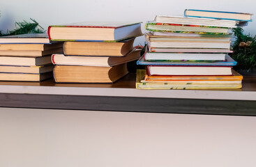 Stacks of books in colorful covers on table near white wall