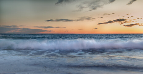Waves in the Mediterranean sea with orange sunset.