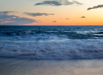 Fototapeta na wymiar Waves in the Mediterranean sea with orange sunset.