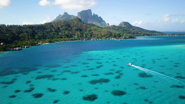 4K Aerial Drone footage of a cruising boat and Mount Otemanu in Bora Bora, Tahiti, French Polynesia. Turquoise blue lagoon in Bora Bora. Luxury, romantic vacation, honeymoon exotic destination.