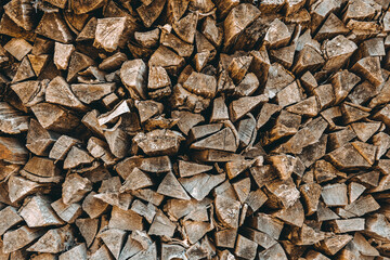 Chopped firewood pile. Woodpile wall. Heap of old dry pine woods. Brown textured background. Natural solid fuel resources. Winter preparation. Countryside pattern. Rustic style details. Woodworking