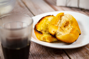 Coffee and Bread toasted with butter on the plate. It is a traditional Brazilian breakfast. Selective focus. 