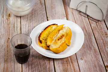 Coffee and Bread toasted with butter on the plate. It is a traditional Brazilian breakfast. Selective focus. 