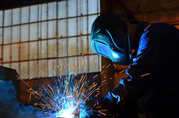 Workers wearing industrial uniforms and Welded Iron Mask at Steel welding plants, industrial safety first	
