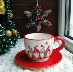 Obraz na płótnie Canvas beautiful Christmas cup with gnomes for hot drinks on the background of cones and a star. decorative composition for home decoration during the celebration of christmas and new year