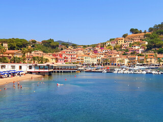 Fototapeta na wymiar City of Porto Azzuro with colorful houses and tourists on the beach.