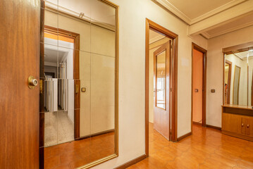 Entrance hall of a house with a full-length mirror, ugly brown tiled floors and woodwork on doors and skirting boards
