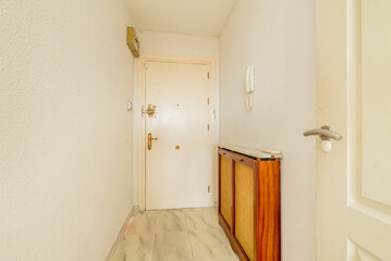 Lobby of a house with a solid wood access door, painted white and a radiator cover with grilles