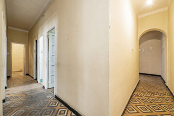 L-shaped corridors of an old house without reforms since it was built with worn and dirty hydraulic...