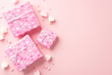 Valentine's Day concept. Top view photo of big present boxes heart shaped marshmallow and sprinkles on isolated pastel pink background with empty space