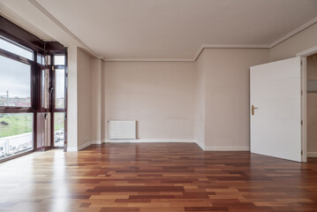 Fototapeta premium A living room with reddish wooden flooring, a window with dark red anodized aluminum and white woodwork