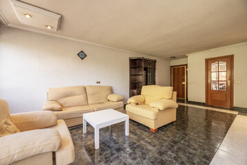 Living room with a two-tone stoneware floor, antique furniture, a large window, a yellow fabric sofa, a white wooden coffee table