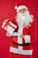 Portrait von einem verkleideten Weihnachtsmann mit Geschenk, isoliert auf roten Hintergrund im Studio im Hochformat