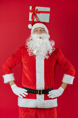 
Portrait von einem verkleideten Weihnachtsmann mit Geschenk, isoliert auf roten Hintergrund im Studio