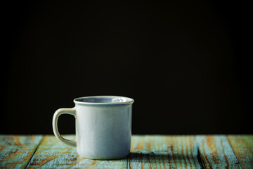 Blue porcelain cup on a blue plank table and black background