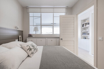 Bedroom with a double bed, a window on one side and white and gray lacquered woodwork