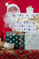 
Portrait von einem verkleideten Weihnachtsmann mit Geschenk, isoliert auf roten Hintergrund im Studio