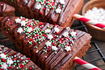 Chocolate brownies Christmas tree with chocolate icing and festive sprinkles on wooden table. Christmas food ideas sweet homemade Christmas holidays pastry concept. Holiday cooking concept. Top view.