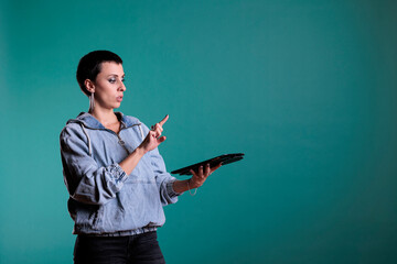 Cheeful woman holding tablet computer using holographic database interface with augmented reality, standing in studio with isolated background. Female having futuristic experience using technology.