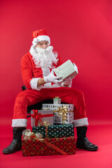 Portrait von einem verkleideten Weihnachtsmann mit Geschenk, isoliert auf roten Hintergrund im...