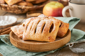 Hand pies. Mini puff pastry or hand pies stuffed with apple and sprinkle sugar powder in wooden plate. Homemade pie snack with crust for breakfast rustic photo.  Copy space.