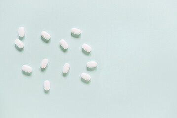 Scattered white pills on blue table. Mock up for special offers as advertising, web background or other ideas. Medical, pharmacy and healthcare concept. Copy space. Empty place for text or logo