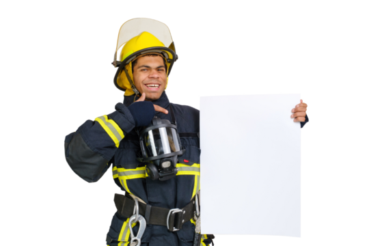 Young smiling African American fireman wearing uniform and helmet looking to the camera and holding blank paper sheet in hand and finger pointing. Copy space for text, isolated on white background 